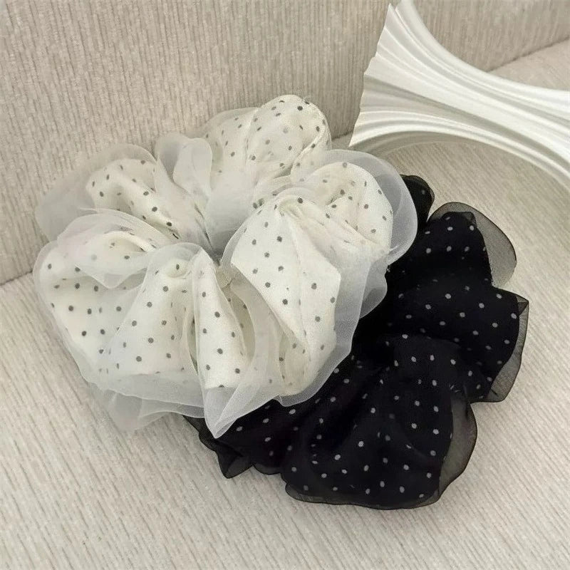 A display of black and white polka dot mesh scrunchie hair ties, featuring soft fabric textures.