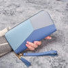 A light blue and purple geometric PU leather wallet with a gold chain is held by a hand on a gray surface.
