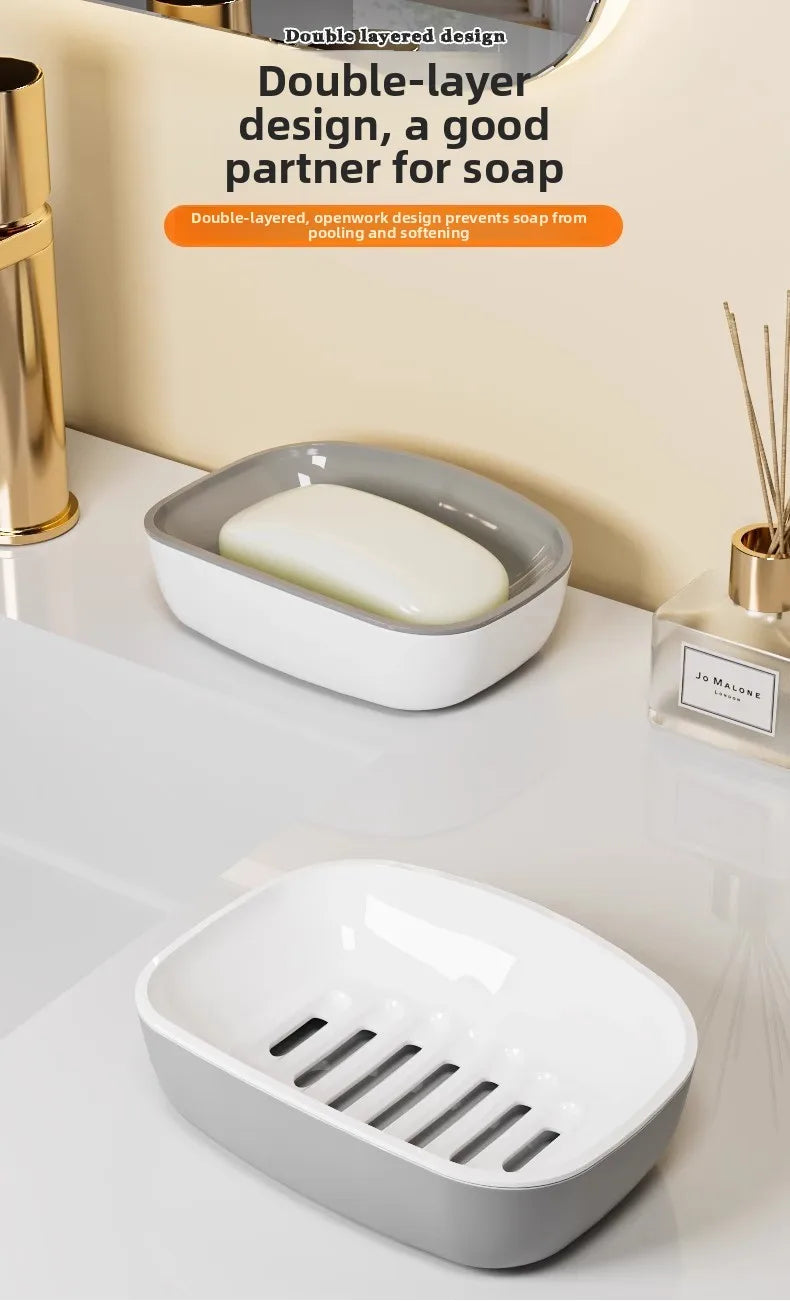 A white double-layer draining soap dish with a non-slip base is shown on a light surface.