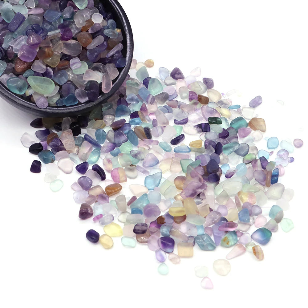 A pile of tumbled crystal stone chips in various shades of purple, blue, and green.
