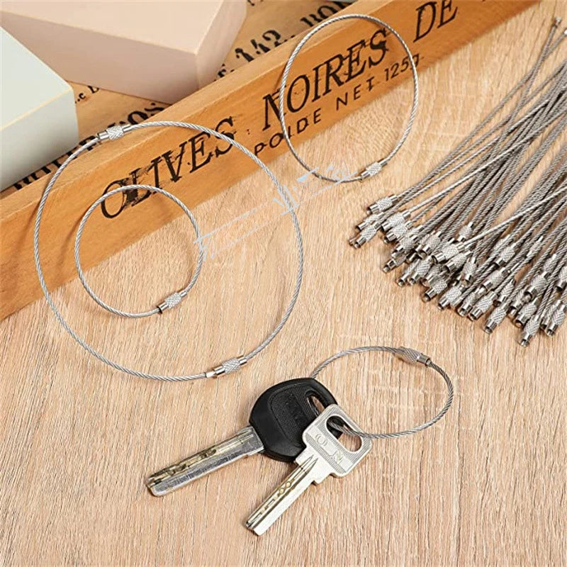Stainless steel wire keychain cable with screw lock displayed on a wooden surface.