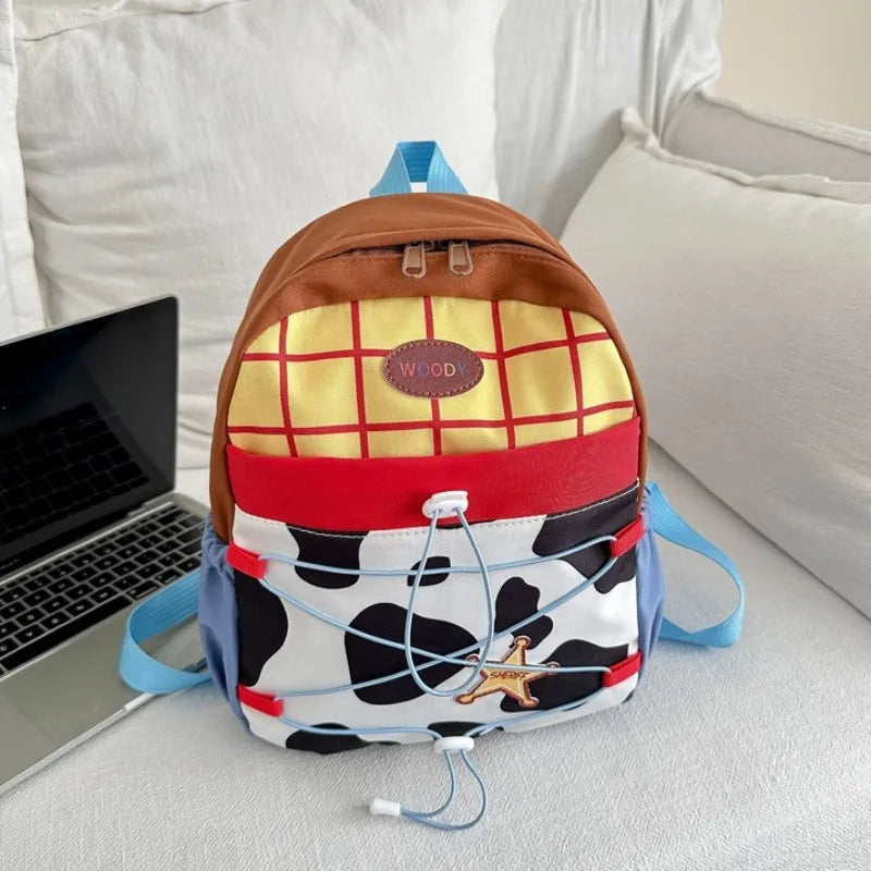 A brown and yellow plaid backpack with a cow print front and blue straps resting on a white surface.