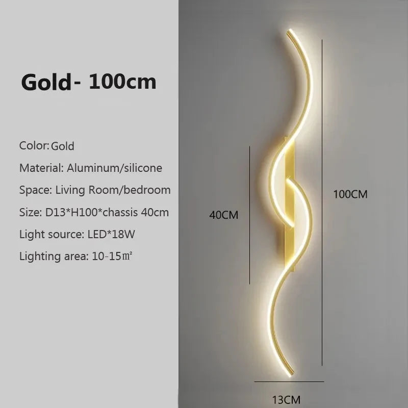 A vertical gold LED wall lamp with a curved design mounted on a wall.