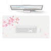 A white waterproof PU leather desk pad featuring a keyboard and mouse, decorated with pink cherry blossoms.