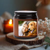 A personalized photo scented soy candle in a dark glass jar resting on a wooden slice.