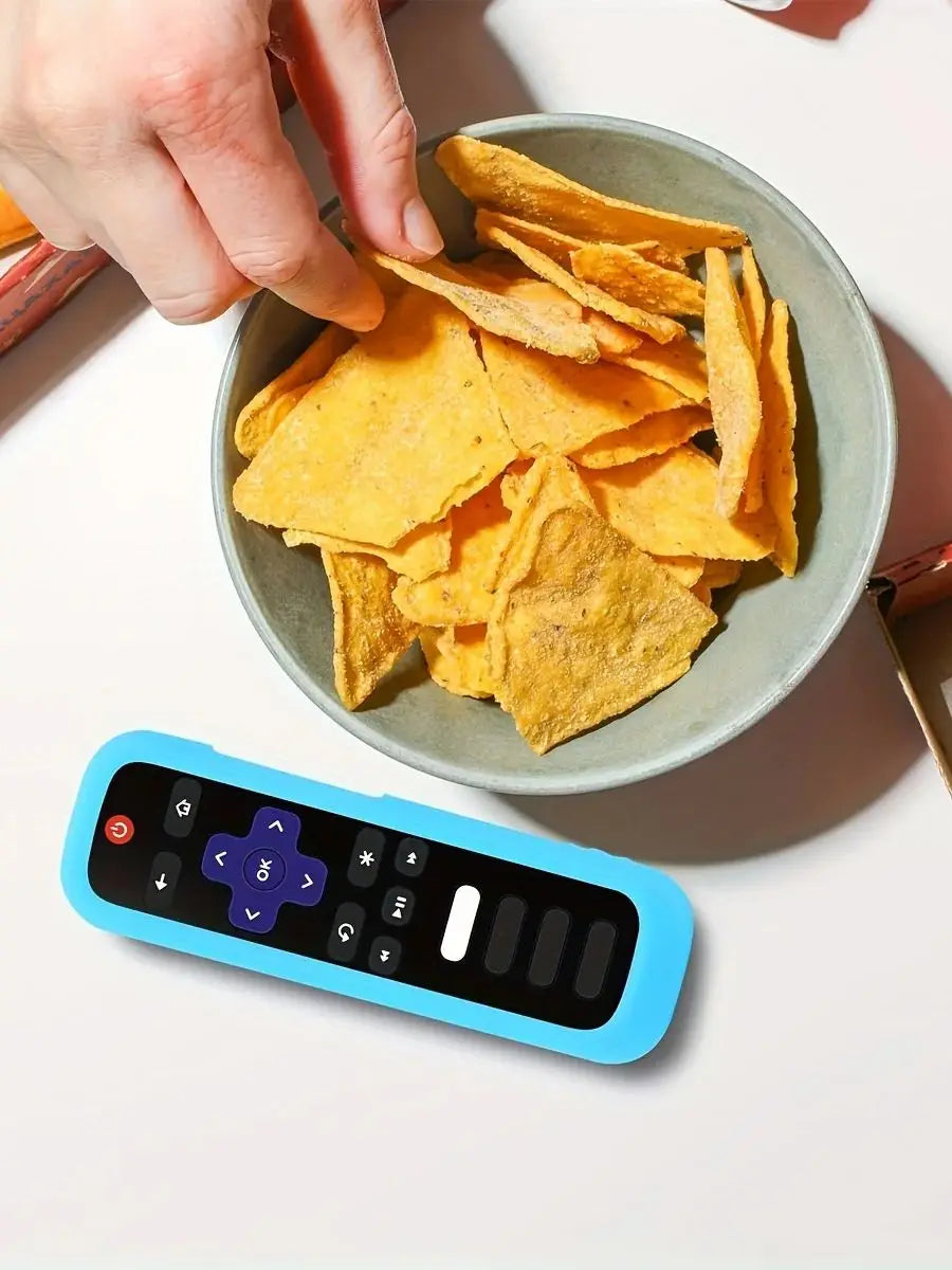 A hand is holding a bowl of crispy yellow chips next to a blue silicone TV remote cover.