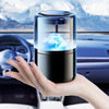 A hand holds a sleek black smart car diffuser with ambient light and auto mist in a car interior setting.