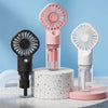 A pink and white portable USB rechargeable mist fan with a clear bottle is displayed on a textured surface.