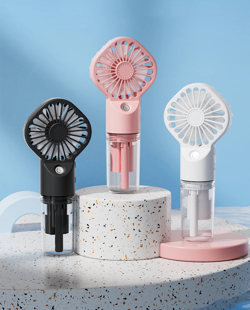 A pink and white portable USB rechargeable mist fan with a clear bottle is displayed on a textured surface.