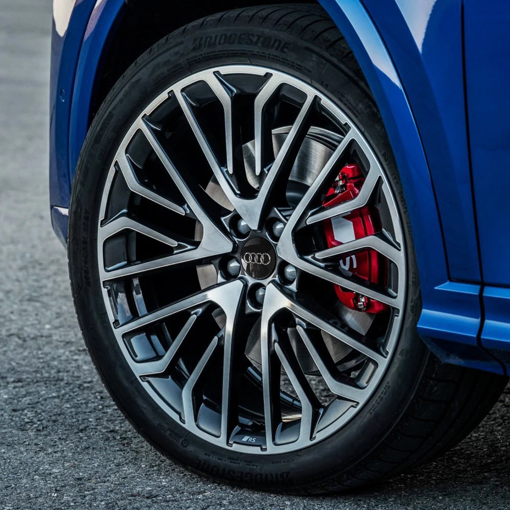 Close-up of a blue Audi wheel with black and silver decorative alloy rims and a red brake caliper.