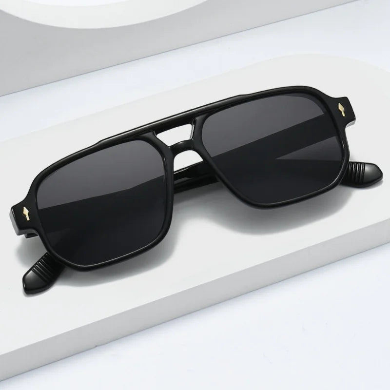 Black retro double-bridge square sunglasses resting on a white surface.