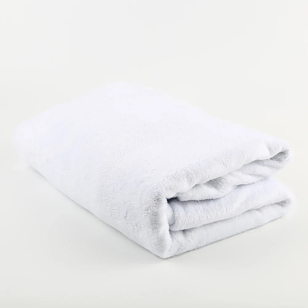 White fleece throw blanket folded neatly on a white surface.