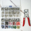 A clear plastic box containing various metal snap buttons in different colors and finishes.