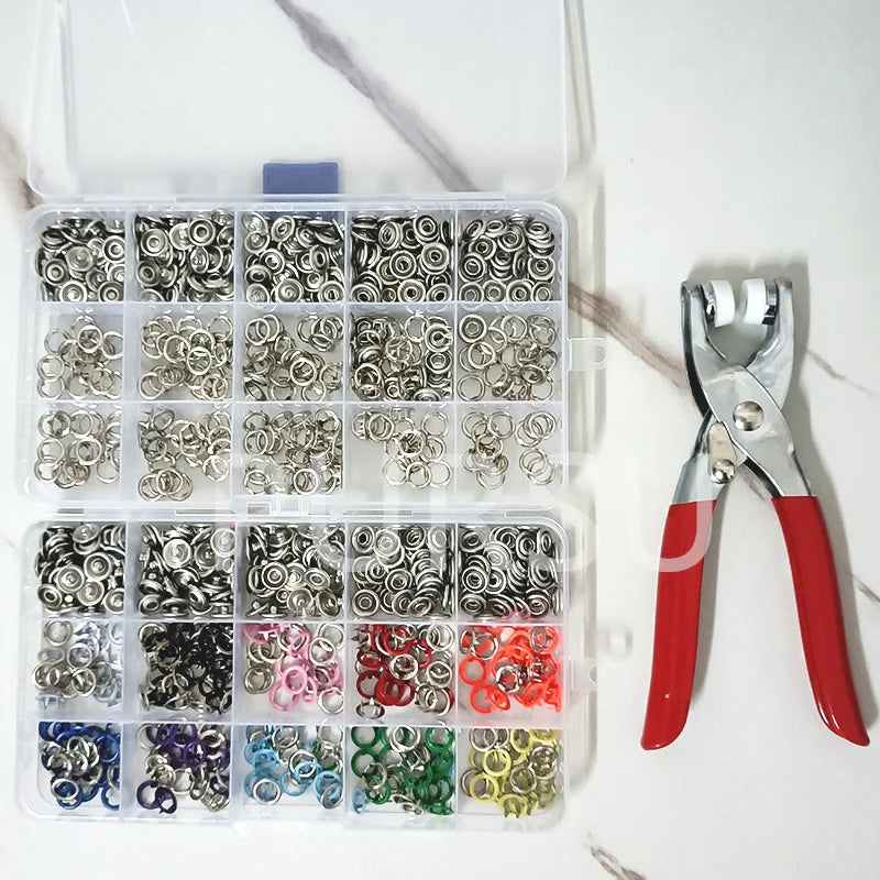 A clear plastic box containing various metal snap buttons in different colors and finishes.