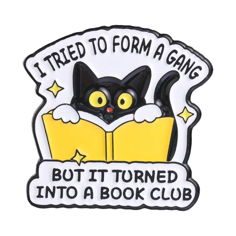 Enamel pin featuring a black cat looking out of an open yellow book with text that reads I tried to form a gang but it turned