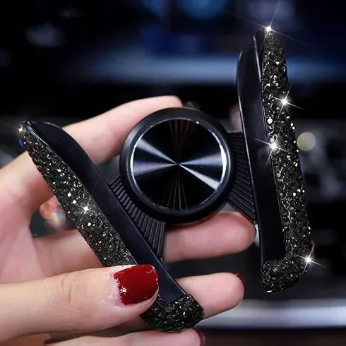 A hand holds a black crystal air vent car phone holder with a textured finish.