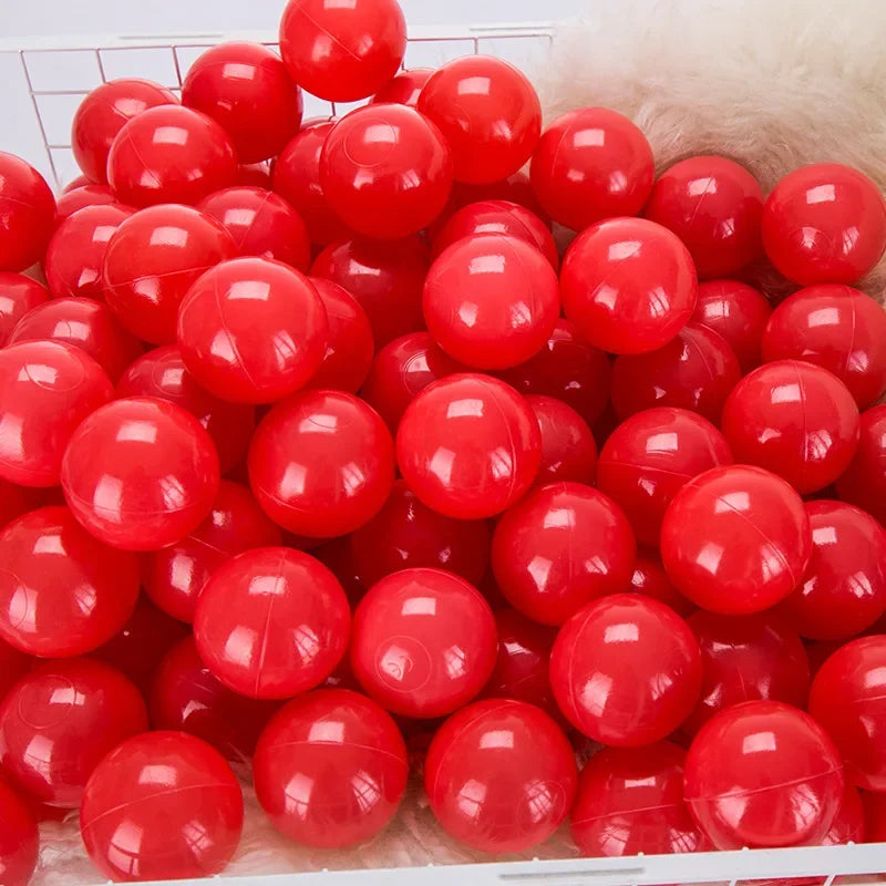 A large quantity of bright red, glossy plastic ball pit balls for toddlers and kids are displayed in a white crate.