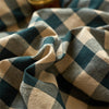 A close-up of a plaid duvet cover fabric in shades of dark teal, beige, and gray.