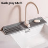 Dark gray silicone faucet splash mat with a curved metal faucet installed in a white kitchen sink.