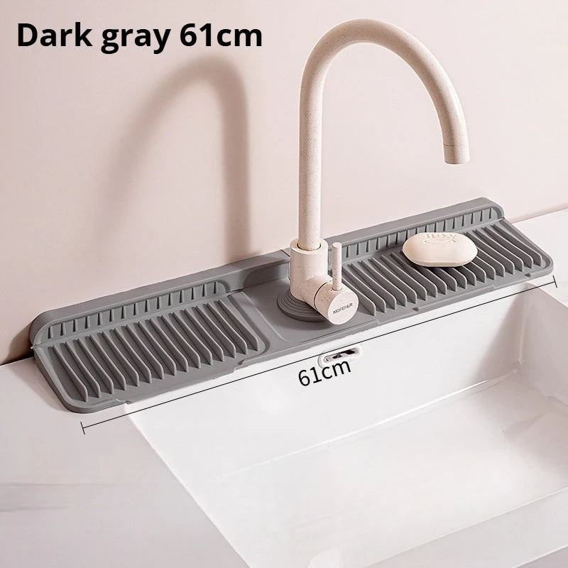 Dark gray silicone faucet splash mat with a curved metal faucet installed in a white kitchen sink.