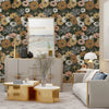 A room decorated with a dark green and white floral wallpaper, gold accents, and light wood furniture.