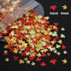 A scatter of shiny holographic star sequins in red, orange, and gold colors are displayed on a dark surface.