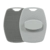 A gray silicone body scrubber and massage brush with textured surfaces.