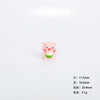 A small pink resin figurine of a pig holding a green item, used as miniature garden or desk décor.