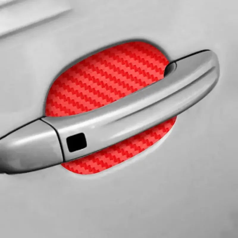 A close-up of a silver car door handle with a red carbon fiber protective cover placed on it.