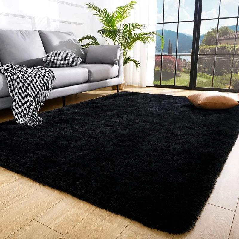 A luxurious black velvet plush carpet placed on a light wood floor in a modern living room setting.