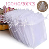 A stack of 100 white organza drawstring bags for gifts and party favors