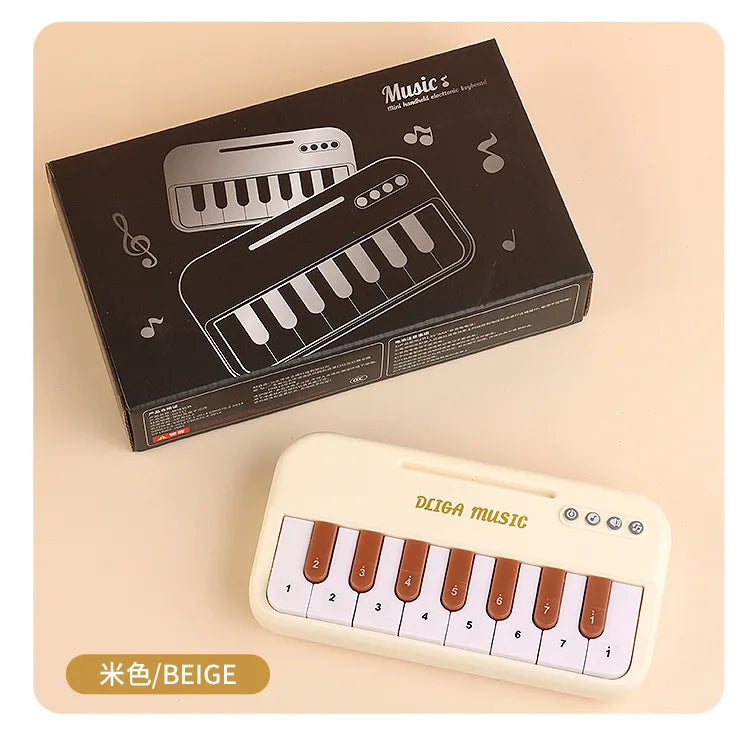 A beige mini 15-key electronic keyboard piano is shown next to its original packaging box.