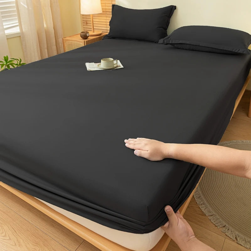 A dark gray fitted sheet is laid on a bed, showing the elastic edge and fabric texture.