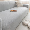 A light gray plush sofa cover with a decorative cushion and a small tray of food on the seat.
