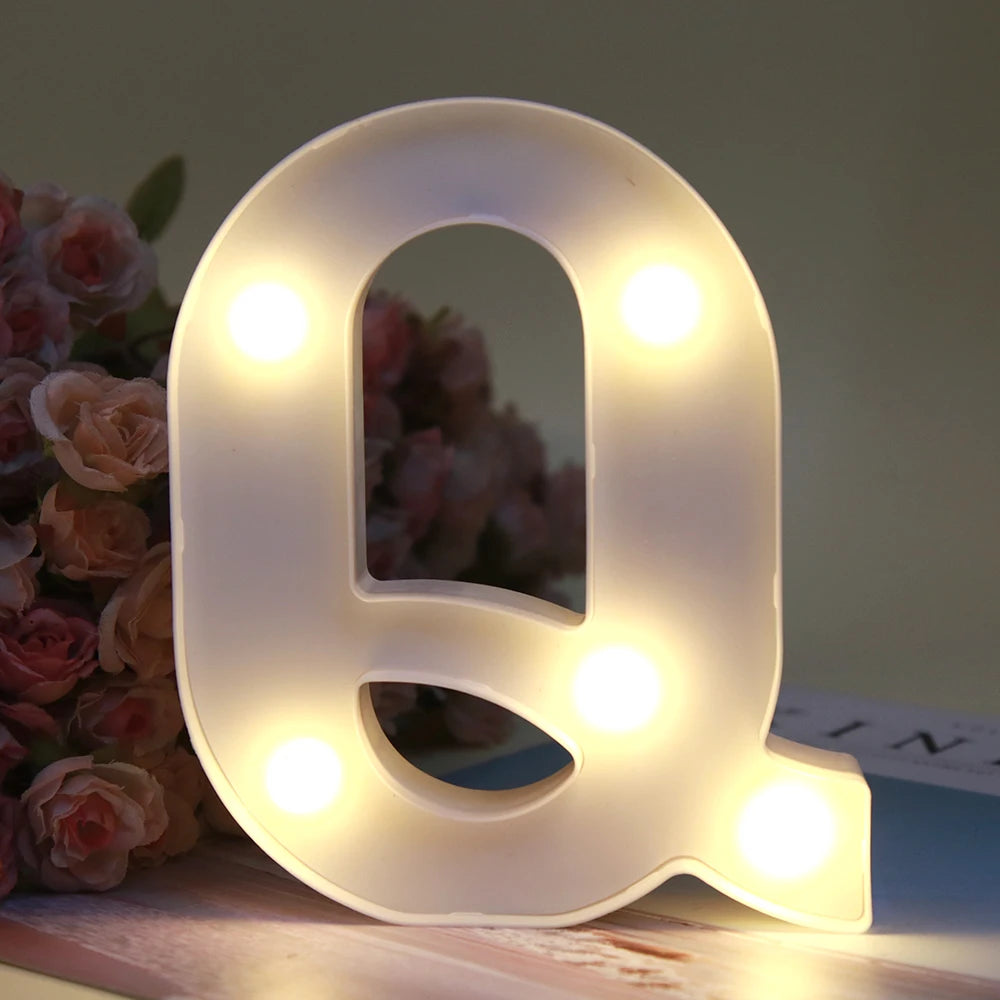 Lumière de nuit alphabet LED blanche en forme de lettre Q posée sur une surface en bois.