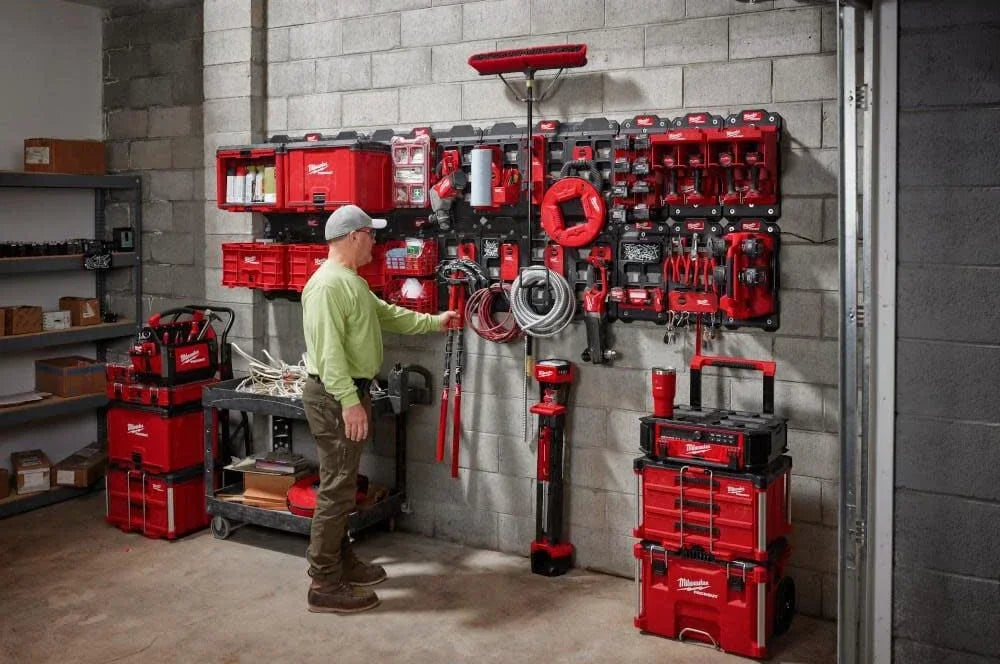 A wall display of red PACKOUT magnetic bins and tools mounted on a gray concrete wall.