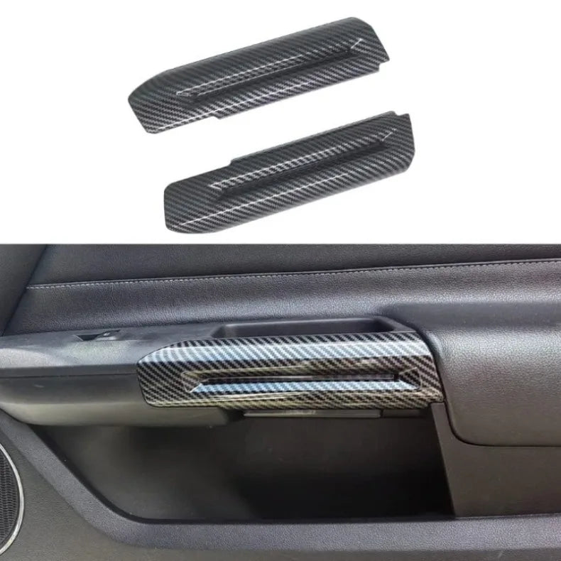 Two carbon fiber door handle covers for a Ford Mustang, shown against a dark car interior background.