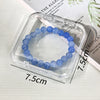 A bracelet of light blue beads is displayed inside a clear jewelry organizer box.