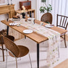 A wooden dining table set with a sheer floral tulle table runner and matching tableware.