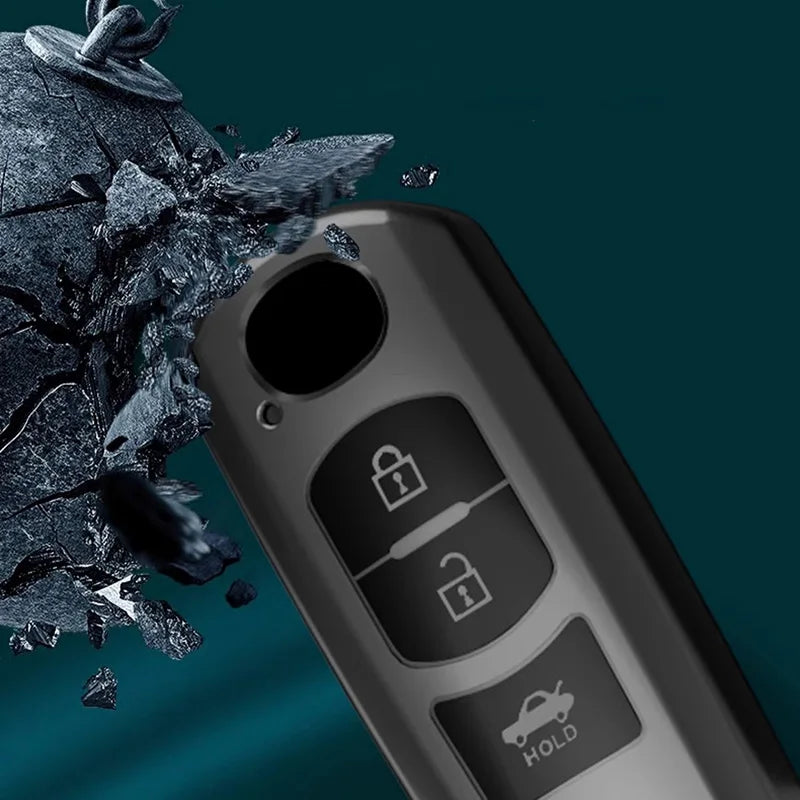 Close-up of a black TPU car key cover with security features and a piece of broken glass in the background.