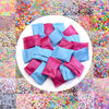 A circular display of various shades of pink and blue acrylic beads used for jewelry making.
