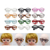A collection of transparent plastic sunglasses for dolls in various colors and styles.