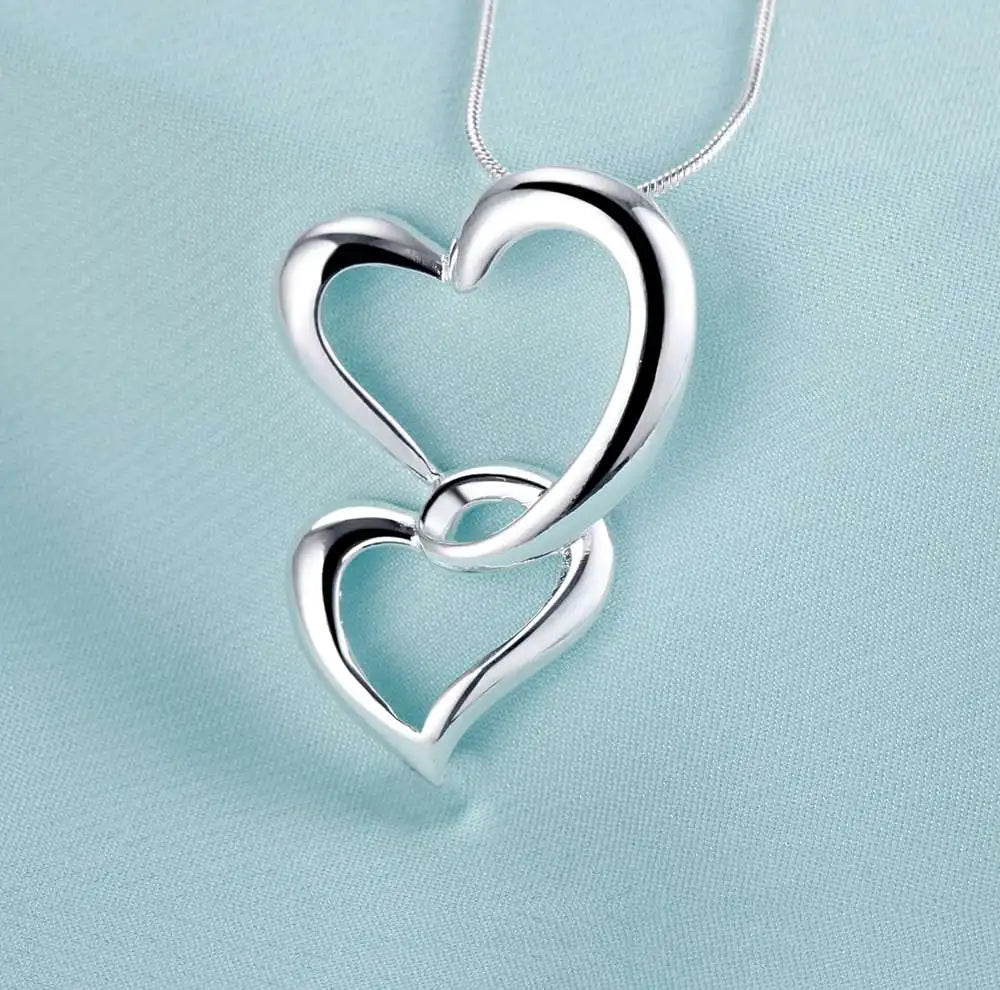 Collier pendentif en argent avec deux cœurs entrelacés sur une chaîne délicate.