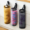 Wall-mounted mesh bag dispenser with three vertical bags in gold, pink, and purple colors