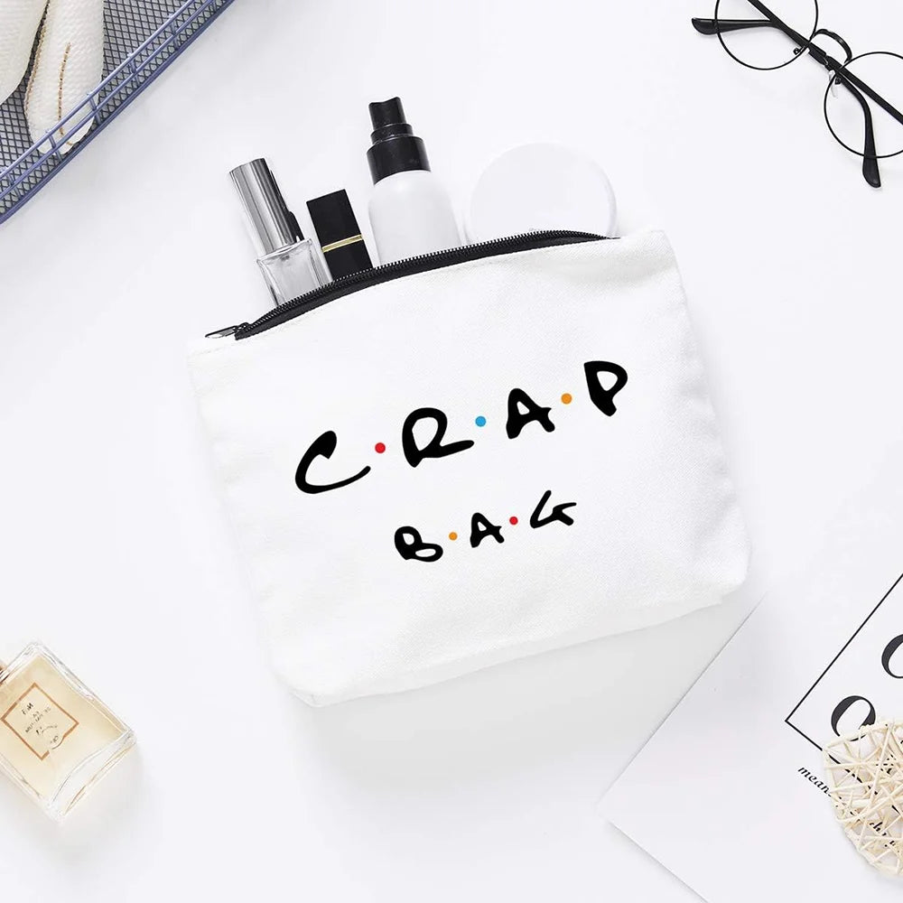 A white toiletry bag with black text reading CRAP BAG, containing various grooming products.