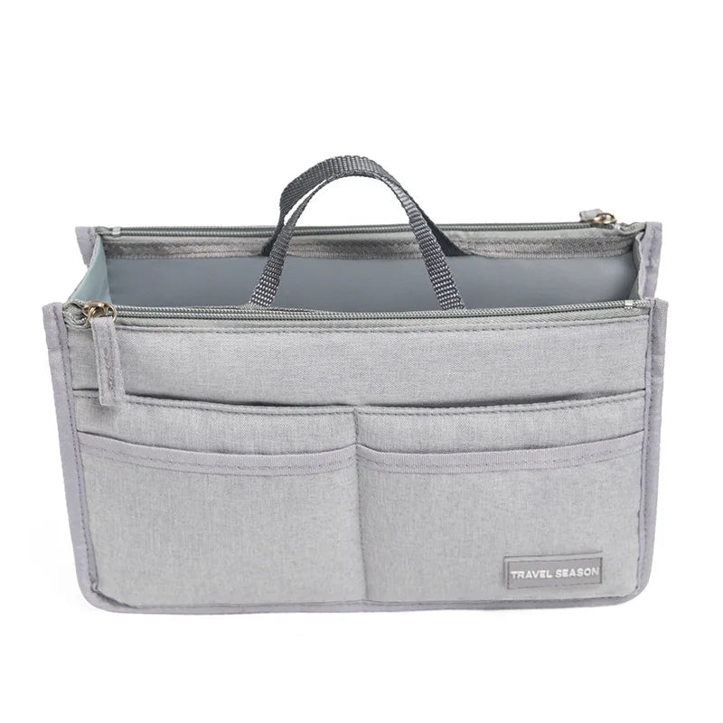 A gray purse organizer insert with multiple compartments and a carrying handle.