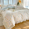 A floral ruffle cotton duvet cover set with light blue and white patterns displayed on a bed.