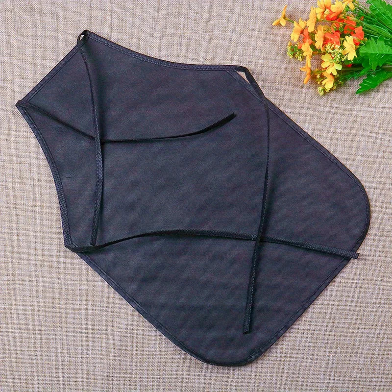 Navy blue non-woven fabric craft apron shown flat on a beige background with some yellow flowers nearby.