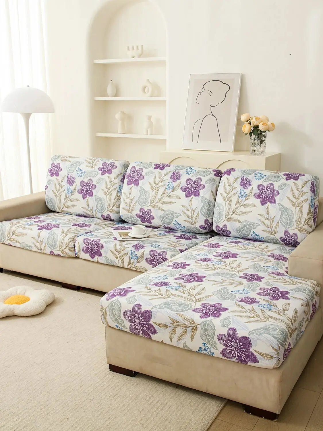 A floral elastic sofa cover in purple and green patterns protecting a beige upholstered sofa.