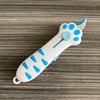 A white retractable cat paw utility knife with blue accents is shown on a gray wooden surface.